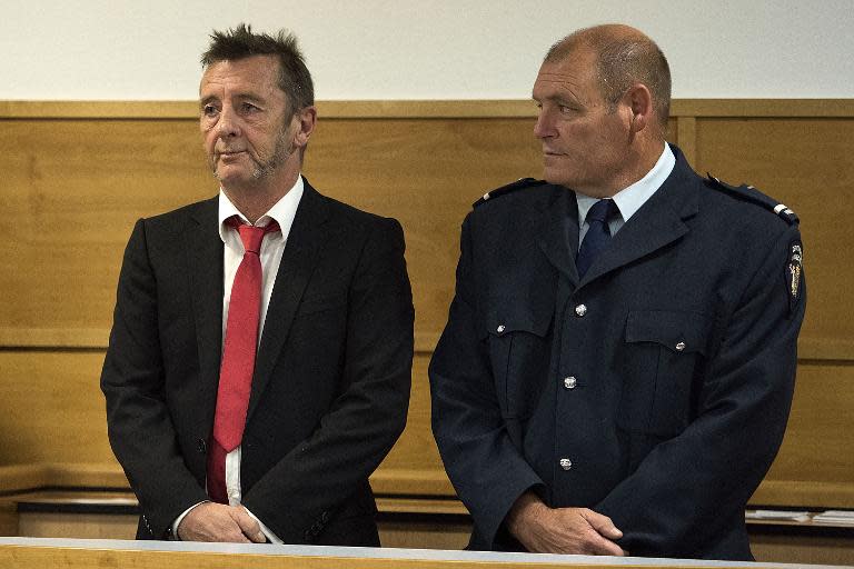Former AC/DC drummer Phil Rudd (L) stands in in the dock flanked by security, facing charges at the District Court in Tauranga, New Zealand, on April 21, 2015