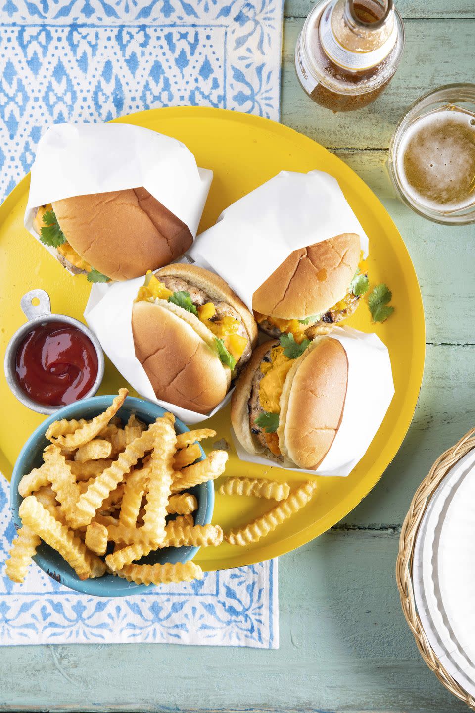 pork burgers with hatch chiles and pepper jack on a yellow serving tray with fries on the side