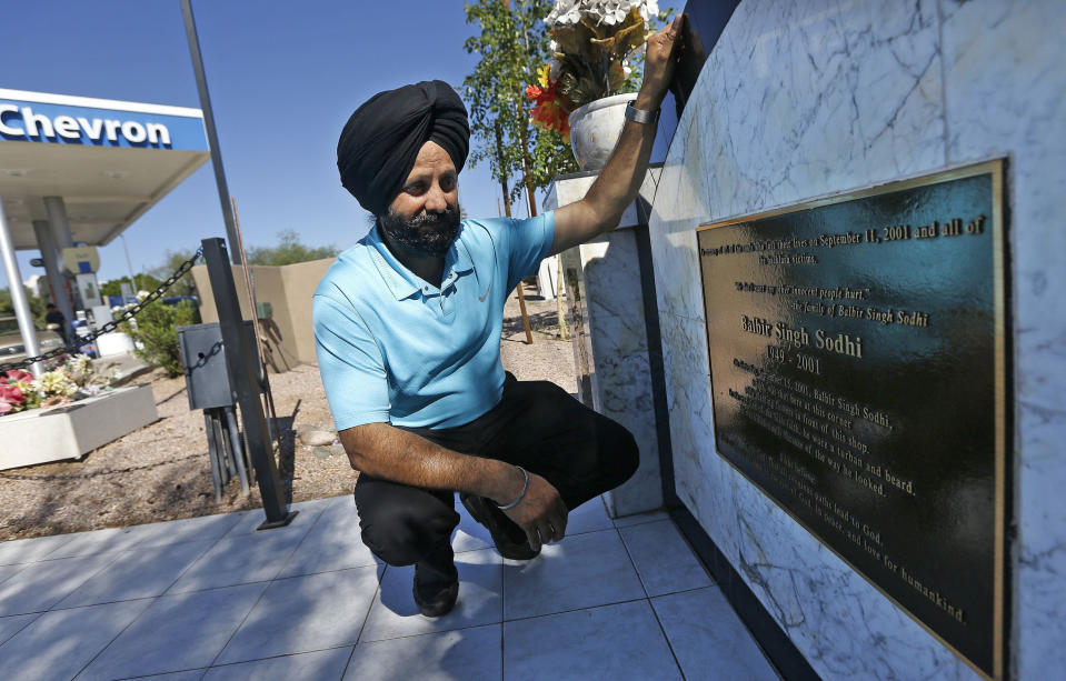 FILE - In this Aug. 19, 2016 file photo, Rana Singh Sodhi, kneels near his service station in Mesa, Ariz., next to a memorial for his brother, Balbir Singh Sodhi, who was murdered in the days after the Sept. 11 terrorist attacks. Sodhi, a Sikh American was killed at his Arizona gas station four days following the Sept. 11 attacks by a man who announced he was "going to go out and shoot some towel-heads" and mistook him for an Arab Muslim. (AP Photo/Ross D. Franklin, File)