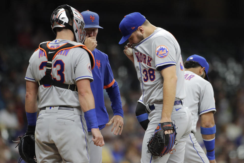 New York Mets' Tylor Megill (38) talks with pitching coach Jeremy Hefner, second from left, and teammates during the fourth inning of a baseball game against the Milwaukee Brewers, Friday, Sept. 24, 2021, in Milwaukee. (AP Photo/Aaron Gash)