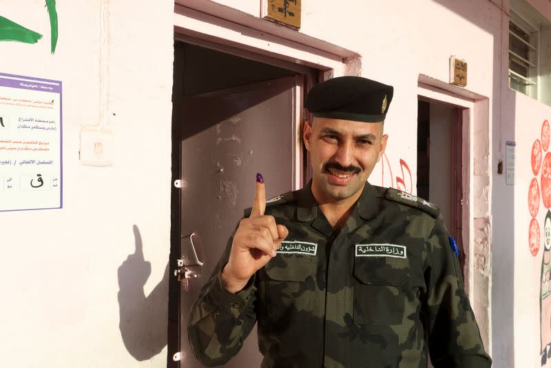 Police officer shows his ink-stained finger after voting in Baghdad