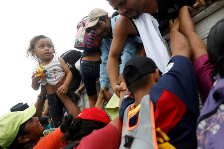 Honduran migrants, part of a caravan trying to reach the U.S., go up for a truck during a new leg of their travel in Zacapa, Guatemala October 17, 2018. REUTERS/Edgard Garrido