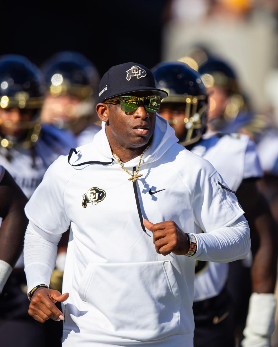 Colorado football coach Deion Sanders runs onto the field for an Oct. 7 game against Arizona State.