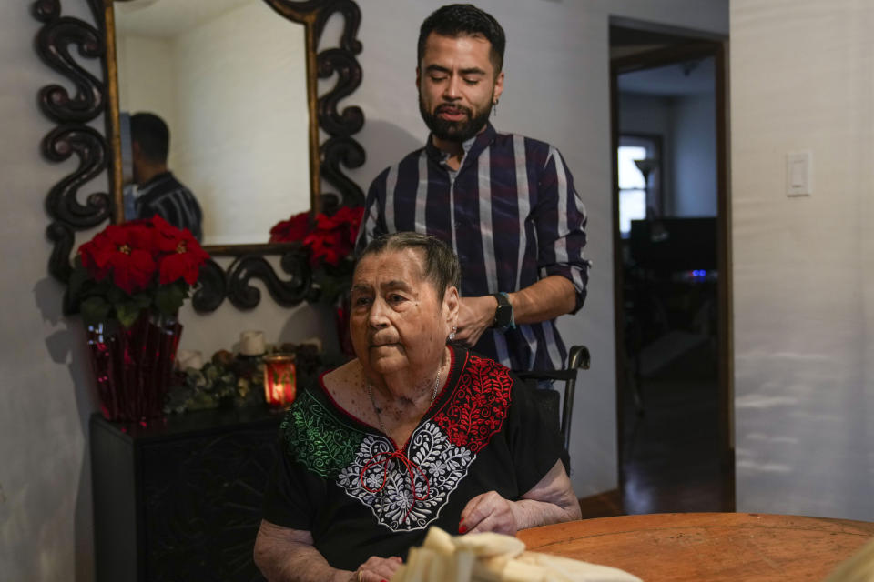 Joaquin Sanchez plays with the hair of his grandmother Aurora Sandoval as they wait for the next step in tamale-making with family members at the family home Tuesday, Dec. 26, 2023, in Chicago. When she was 1, Noelia Sanchez and her mother Aurora, who had no work documents, were rounded up with dozens of other immigrants in a Texas town near the border. The U.S.-born child and her mother were forced to go to Mexico along with hundreds of thousands of other people. (AP Photo/Erin Hooley)