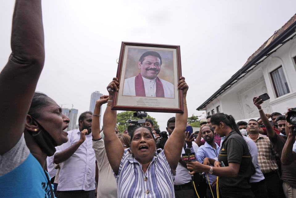 Sri Lankan government supporters shout slogans holding a portrait of prime minister Mahinda Rajapaksa outside his official residence in Colombo, Sri Lanka, Monday, May 9, 2022. Government supporters on Monday attacked protesters who have been camped outside the office of Sri Lanka's prime minster, as trade unions began a "Week of Protests" demanding the government change and its president to step down over the country's worst economic crisis in memory.(AP Photo/Eranga Jayawardena)