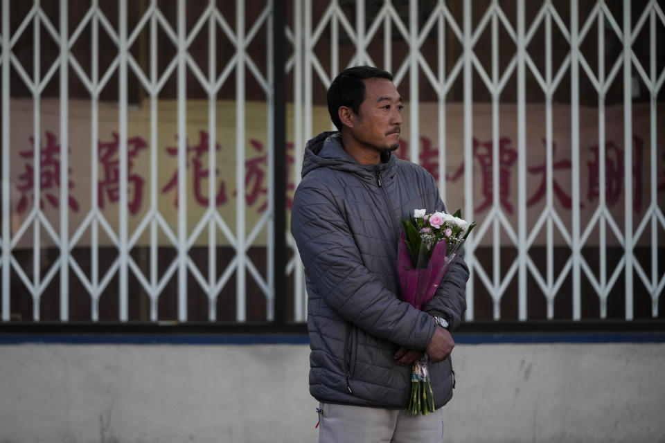 Hunter Zhao, 41, holds flowers to honor the victims killed in Saturday's ballroom dance studio shooting in Monterey Park, Calif., Sunday, Jan. 22, 2023. A gunman killed multiple people at the Star Ballroom Dance Studio late Saturday amid Lunar New Years celebrations in the predominantly Asian American community. (AP Photo/Jae C. Hong)