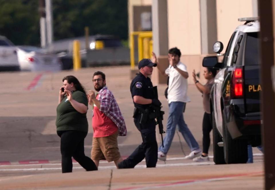 People raise their hands as they leave a shopping center following reports of a shooting, Saturday, May 6, 2023, in Allen, Texas. (AP Photo/LM Otero)