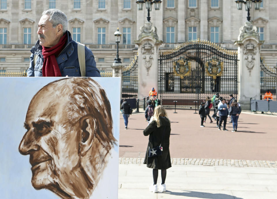 Artist Kaya Mar holds a portrait he has painted of the Duke of Edinburgh outside Buckingham Palace, London, Monday, April 12, 2021. Britain's Prince Philip, the irascible and tough-minded husband of Queen Elizabeth II who spent more than seven decades supporting his wife in a role that mostly defined his life, died on Friday. (Luciana Guerra/PA via AP)