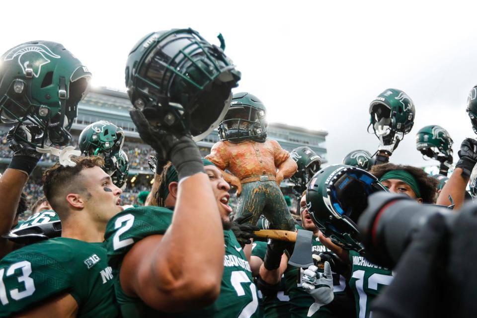 Michigan State players celebrate the 37-33 win over Michigan with the Paul Bunyan trophy at Spartan Stadium in East Lansing on Saturday, Oct. 30, 2021.