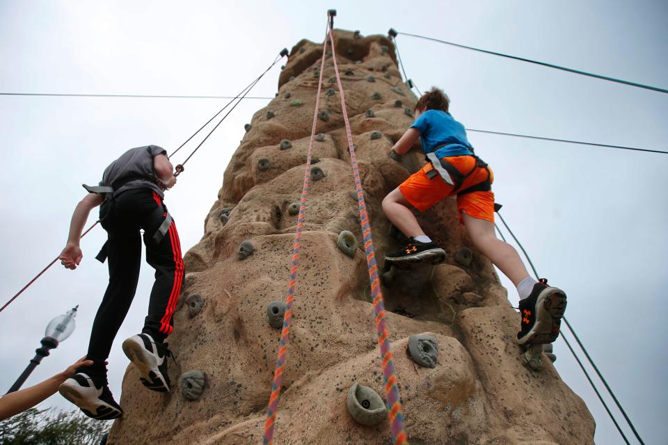 Youngsters climb a rock wall provided by Caribiner's at the Play in the Park program at Hazelwood Park in New Bedford.