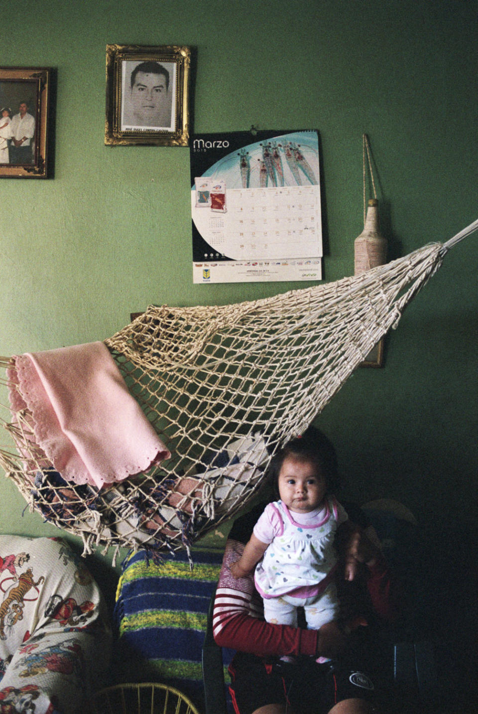 A relative holds Gaby, the baby daughter of missing student Jos&eacute; &Aacute;ngel Campos Cantor, on March 18, 2015.&nbsp;His portrait&nbsp;hangs on the wall behind her. His other daughter, America, is 8 years old.&nbsp;
