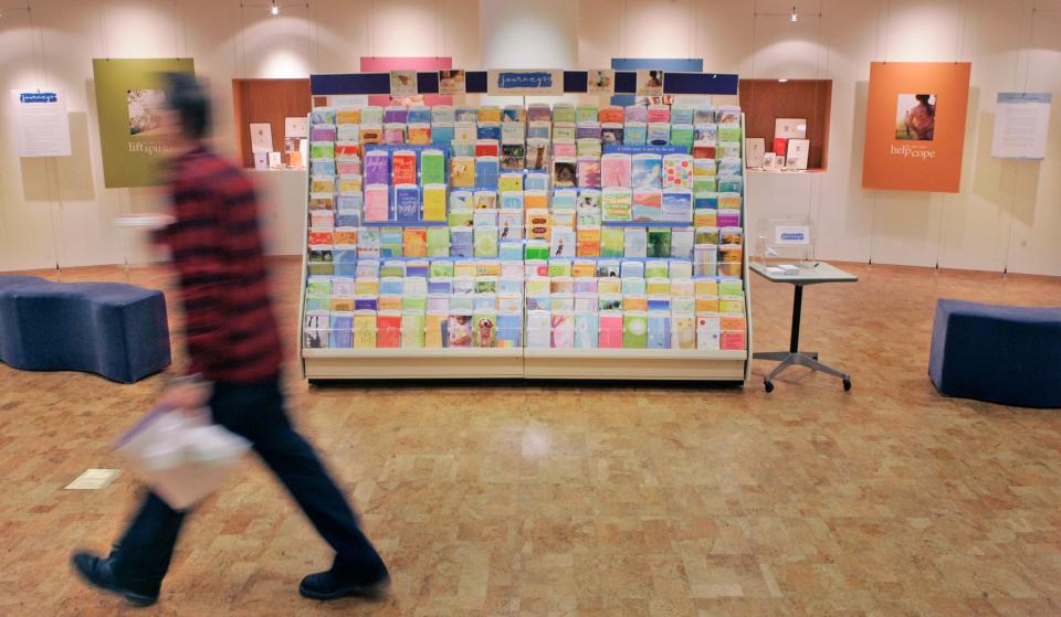 This file photo shows an unidentified worker walking past a display of a new line of cards at Hallmark Cards Inc. in Kansas City, Kan.