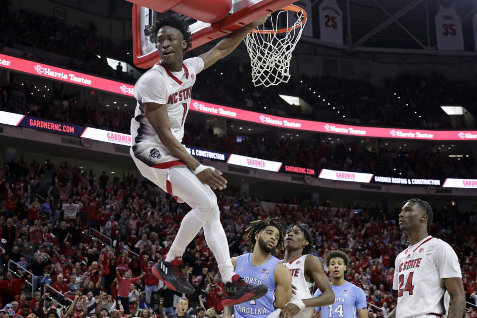 North Carolina State guard Jarkel Joiner (1) follows through on a dunk as North Carolina State guard Terquavion Smith, third from right, and forward Ernest Ross (24) along with North Carolina guard R.J. Davis, fourth from right, and forward Puff Johnson (14) look on during the second half of an NCAA college basketball game, Sunday, Feb. 19, 2023, in Raleigh, N.C. (AP Photo/Chris Seward)