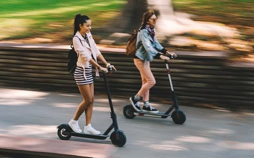 Two women riding escooters