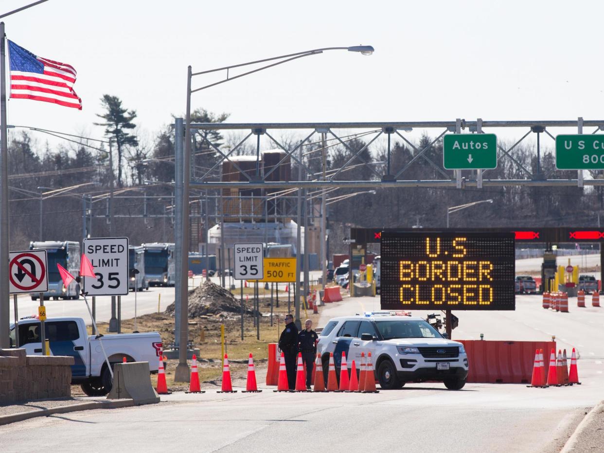 US Customs officers stand beside a sign saying that the US border is closed at the US/Canada border in Lansdowne, Ontario, on 22 March 2020: (2020 Getty Images)