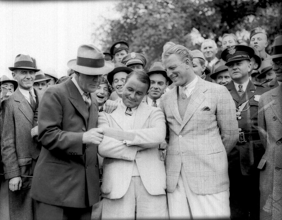 Gene Sarazen (center) receives his $1,500 check for winning the 1935 Augusta National Invitational. Grantland Rice presented the check while runner-up Craig Wood looked on.