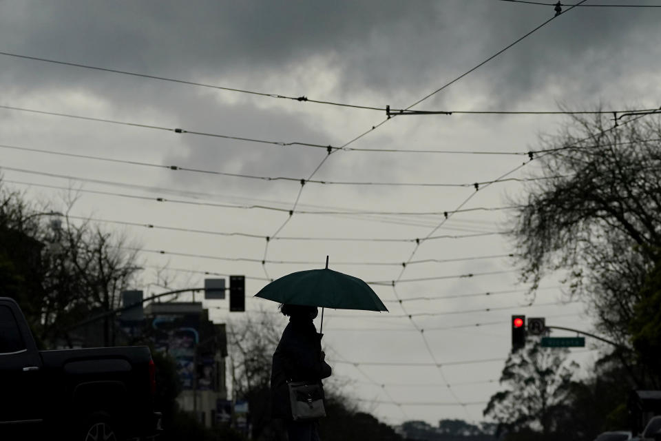 A pedestrian carries an umbrella while crossing the street in San Francisco, Thursday, March 9, 2023. California is bracing for the arrival of an atmospheric river that forecasters warn will bring heavy rain, strong winds, thunderstorms and the threat of flooding even as the state is still digging out from earlier storms. (AP Photo/Jeff Chiu)