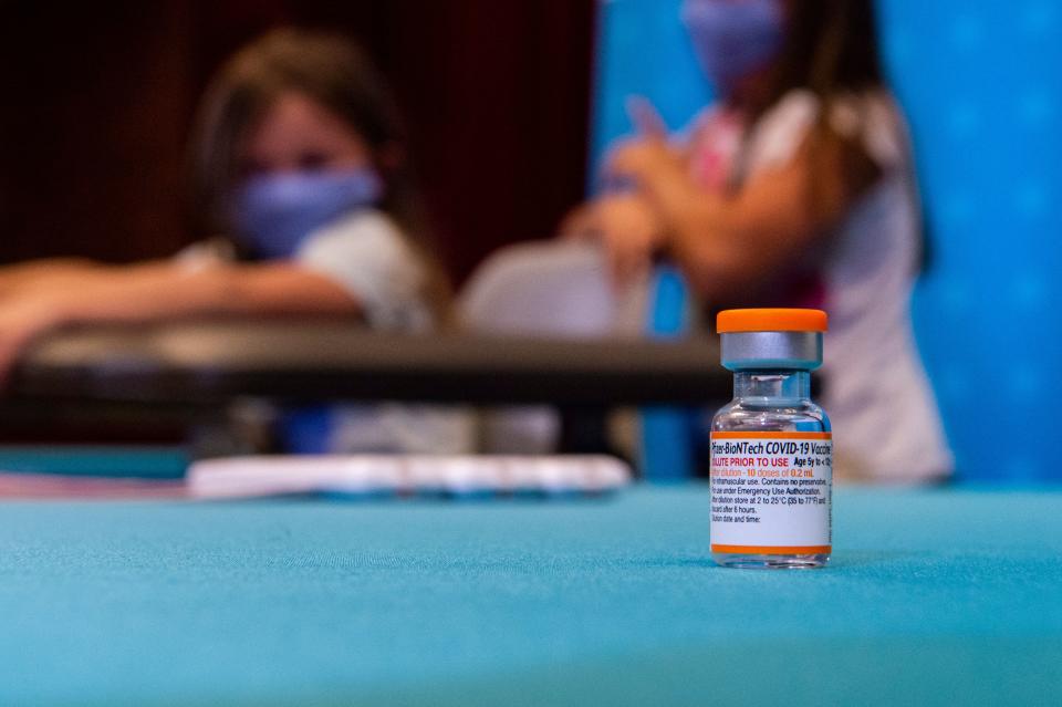 A vial of the new children's dose of the Pfizer-BioNTech Covid-19 vaccine (that will supply ten doses, once reconstituted) sits in the foreground as children play in a hospital room waiting to receive the vaccine at Hartford Hospital in Hartford, Connecticut.