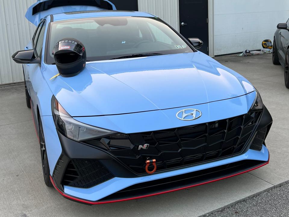 A blue Elantra N with a black helmet sitting on the hood