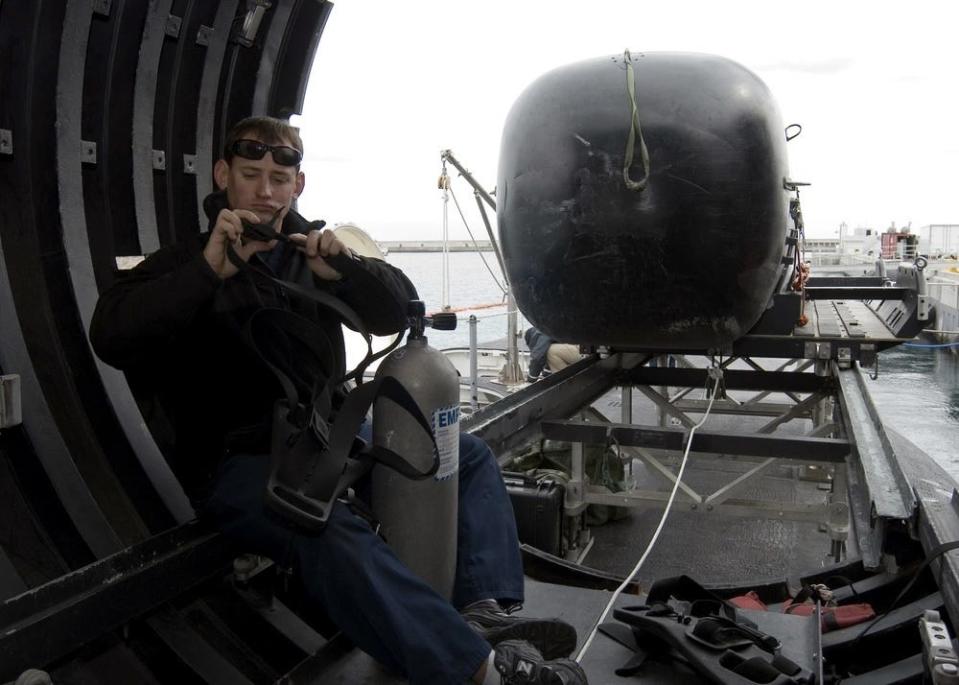 a navy diver sits in a dry deck shelter aboard a missile submarine