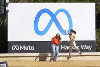 FILE - Facebook employees take a photo with the company's new name and logo outside its headquarters in Menlo Park, Calif., on Oct. 28, 2021, after the company announced that it is changing its name to Meta Platforms Inc. CEO Mark Zuckerberg described the metaverse as a “virtual environment” you can go inside of — instead of just looking at on a screen. (AP Photo/Tony Avelar)