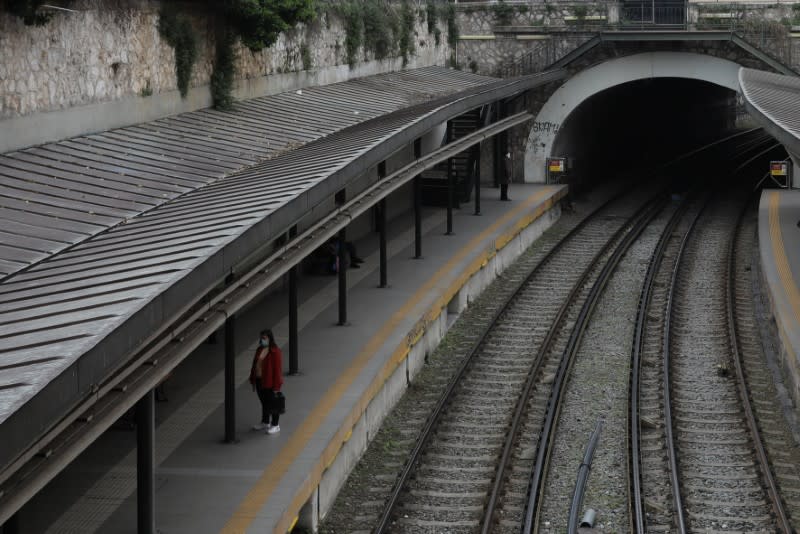 A passenger wearing a protective face mask waits at an almost empty train station, following an outbreak of the coronavirus disease (COVID-19), in Athens