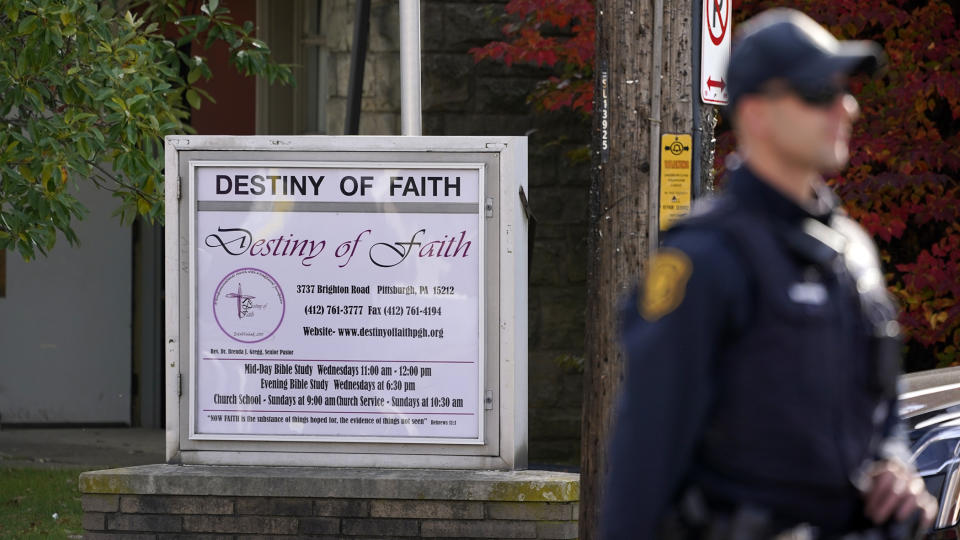 A Pittsburgh police officer stands outside the Destiny of Faith Church in Pittsburgh, Friday, Oct. 28, 2022, where a shooting while a funeral was being held, left six people wounded, including one person who was hospitalized in critical condition. (AP Photo/Gene J. Puskar)
