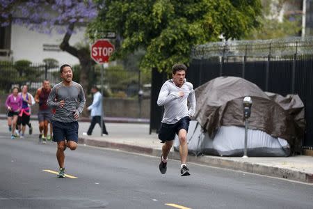 Runners from the Midnight Mission Running Club Phil Peng, 43, (L) and Seth Becker, 22, run through Skid Row in Los Angeles, California April 20, 2015. REUTERS/Lucy Nicholson