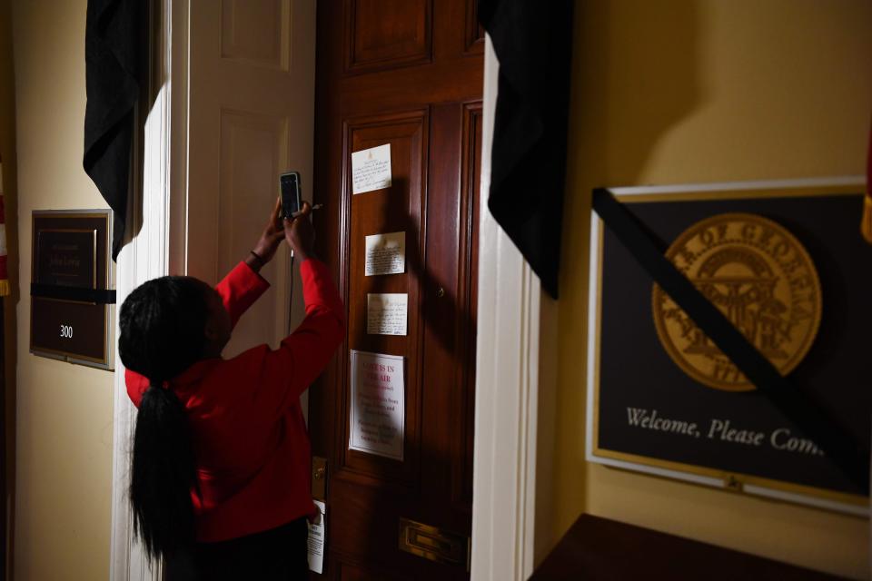 A woman takes a photo of notes left at the office door of John Lewis on July 20 in Washington, D.C.