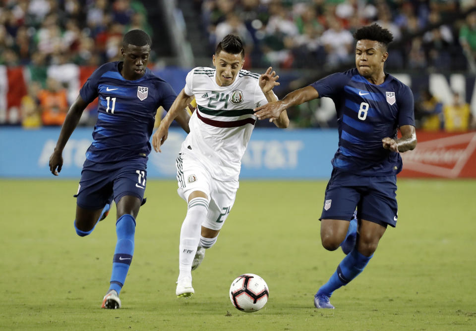 FILE - Mexico midfielder Roberto Alvarado (24) dribbles the ball past U.S. midfielders Tim Weah (11) and Weston McKennie (8) during an international friendly match, Tuesday, Sept. 11, 2018, in Nashville, Tenn. Weston McKennie wants to prove he's worthy to Juventus and its fans. At Juventus, he's a teammate of fellow American Tim Weah, a son of Liberia President and former FIFA Player of the Year George Weah. (AP Photo/Mark Humphrey, File)