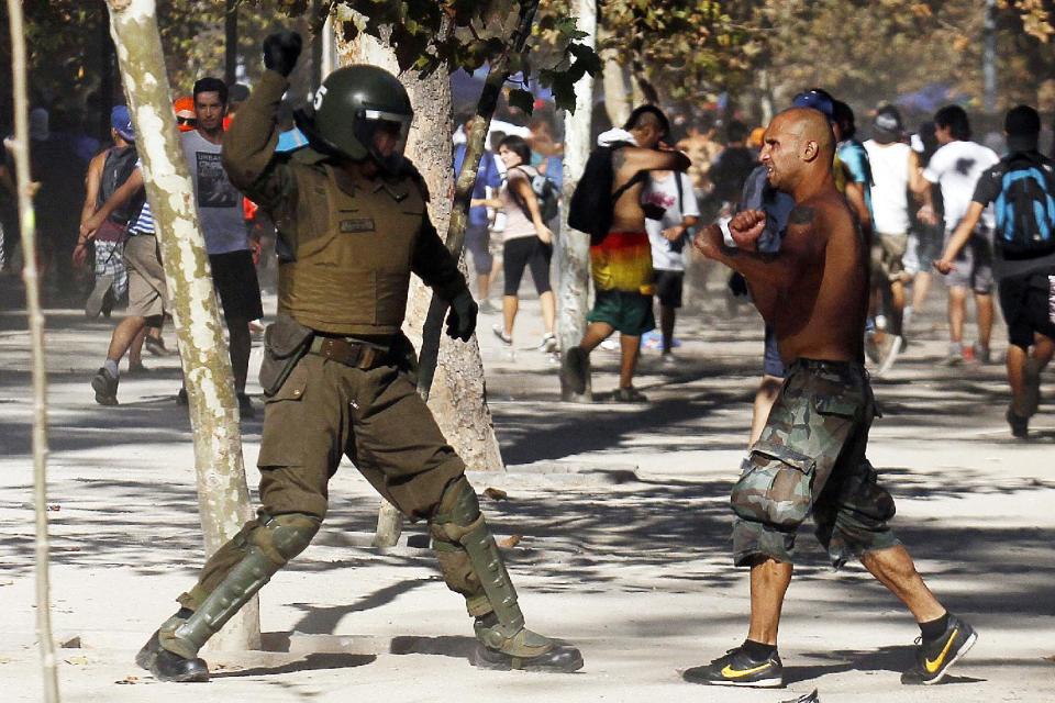 Un manifestante enfrenta a un policía antimotines durante choques violentos al concluir una marcha de protesta en el Parque Forestal, en Santiago, Chile, el sábado 22 de marzo de 2014. (Foto AP/Luis Hidalgo)