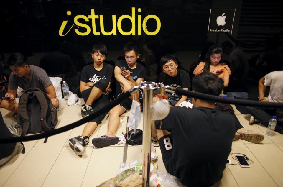 People rest as they queue overnight for the launch of the new Apple iPhone 6s mobile phone at a mall in Singapore