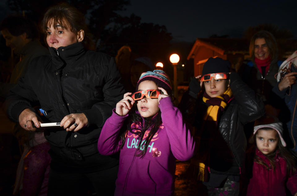 People stand in the dark as they stop to view a total solar eclipse in Chascomus, Argentina, Tuesday, July 2, 2019. A solar eclipse occurs when the moon passes between the Earth and the sun and scores a bull's-eye by completely blocking out the sunlight. (AP Photo/Gustavo Garello)