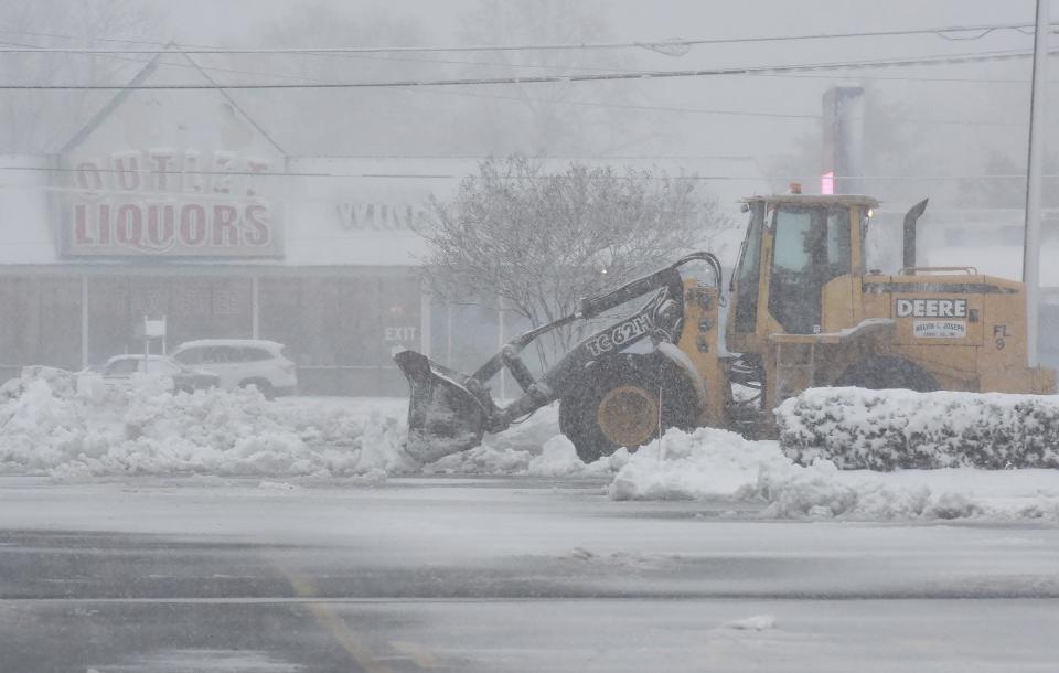 Workers use heavy machinery to remove snow from the Tanger Outlets&#39; parking lot during Monday&#39;s snow storm.