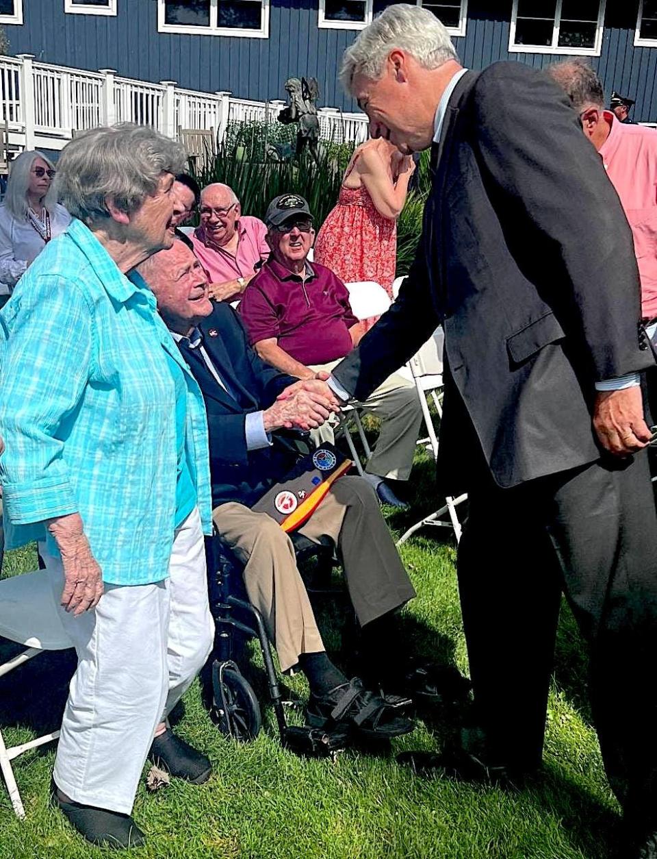 U.S. Sen. Sheldon Whitehouse, right, congratulates Army veteran Francis Marshall for his World War II service as Marshall’s wife, Lois, stands at left.