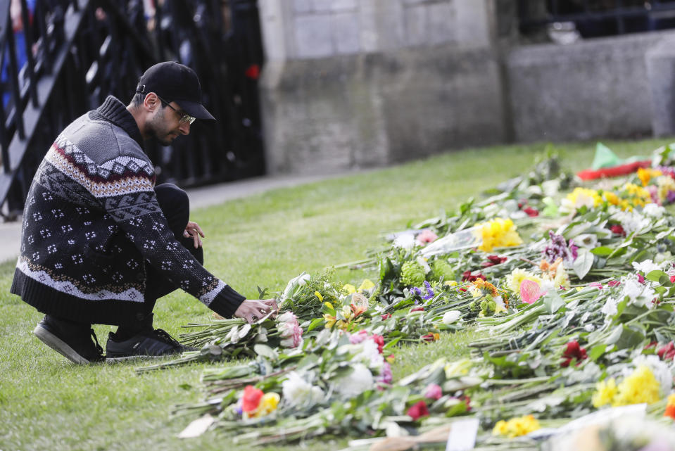 A member of the public lays flowers outside the Cambridge gate of Windsor Castle in Windsor, England after the announcement regarding the death of Britain's Prince Philip, Friday, April 9, 2021. Buckingham Palace officials say Prince Philip, the husband of Queen Elizabeth II, has died. He was 99. Philip spent a month in hospital earlier this year before being released on March 16 to return to Windsor Castle. (AP Photo/Kirsty Wigglesworth)