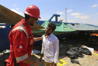 FILE - In this Aug. 1, 2018 file photo, a Tunisian Red Crescent volunteer, left, speaks with a migrant aboard the ship "Sarost 5" docked in the southern Tunisian port of Zarzis, Tunisia. The number of Tunisians migrating clandestinely to Italy has risen to levels not seen since the 2011 Arab Spring uprising. That's causing tensions in Italy's south, where more than 2,200 migrants are quarantining on ferries anchored offshore. (AP Photo/Mounir Beji, File)