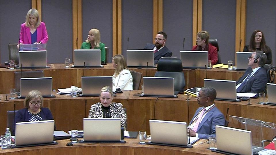 Hannah Blythyn, stood speaking in the Senedd, while Vaughan Gething listens at the front of the picture.