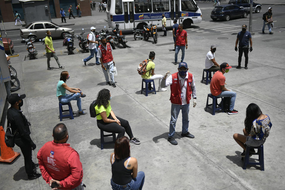 A worker from the Transportation Ministry explains proper mask usage to non-compliant pedestrians on a corner of downtown Caracas, Venezuela, Monday, June 29, 2020, amid efforts to contain the spread of the new coronavirus. (AP Photo/Matias Delacroix)