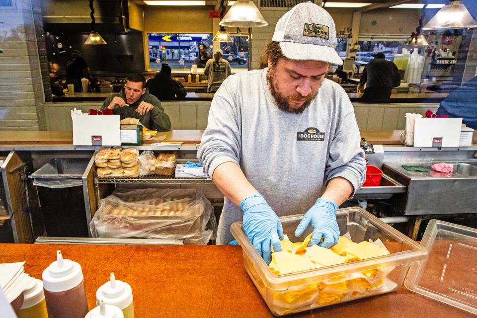 An employees of the landmark restaurant The Dog House grabs some cheese to make cheese dogs at the eatery near New Castle, Thursday, Dec. 7, 2023. The Dog House has been serving hot dogs since 1952 and under new ownership has a new breakfast menu.
