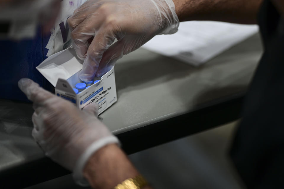 A health worker breaks out a box of COVID 19 vaccine during a mass vaccination event carried out by the Department of Health and the Voces nonprofit organization, at the Miramar Convention Center in San Juan, Puerto Rico, Wednesday, March 31, 2021. (AP Photo/Carlos Giusti)