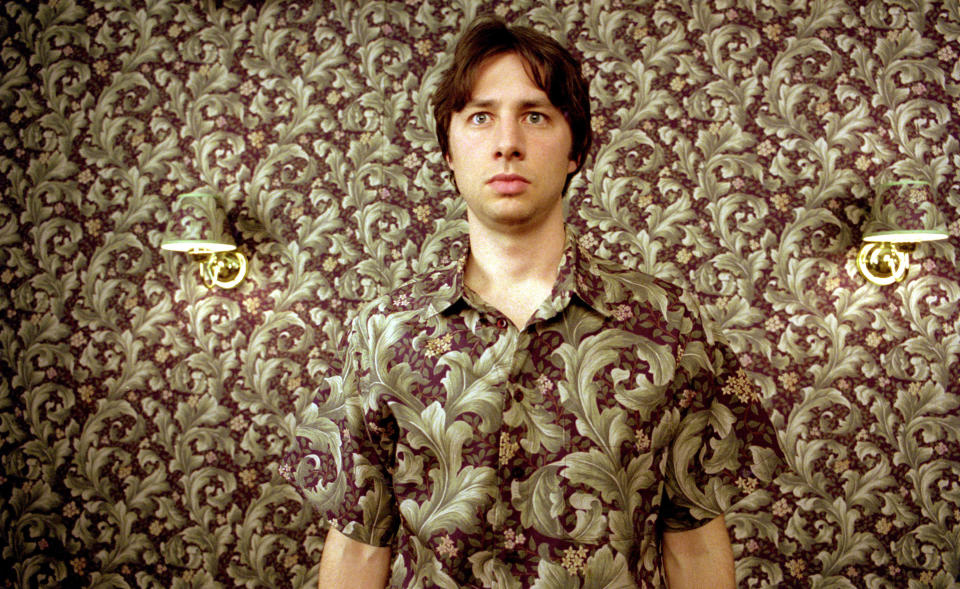 Zach Braff standing in front of a wall.
