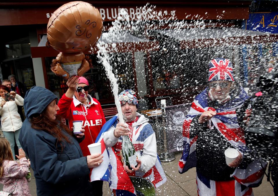 Royal super fans John Loughery (C) pops the cork on a bottle of Champagne, as they stand near Windsor Castle on Monday, following the announcement that Meghan, Duchess of Sussex, has given birth to a son. (Photo: ADRIAN DENNIS via Getty Images)