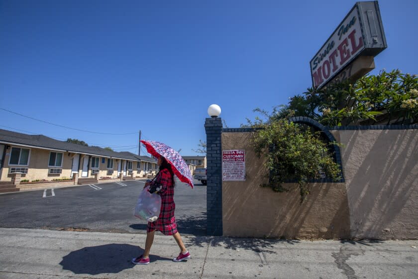 El Monte, CA - June 21: A woman walks past the Siesta Inn Motel in El Monte where two police officers were fatally shot after responding to a call in El Monte, CA on Tuesday, June 21, 2022, in El Monte, CA. (Francine Orr / Los Angeles Times)