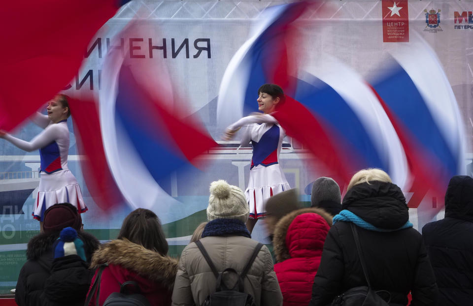 Dancers wave Russian flags during celebration of the anniversary of Crimea annexation from Ukraine in 2014, in St. Petersburg, Russia, Thursday, March 18, 2021. Residents of cities in Crimea and Russia are holding gatherings to commemorate the seventh anniversary of Russia's annexation of the Black Sea peninsula from Ukraine. (AP Photo/Dmitri Lovetsky)