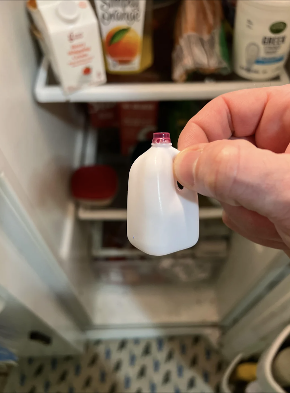 A person holding a miniature milk jug