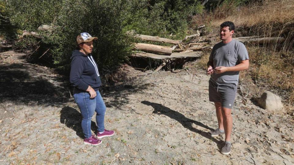 Jamie Lind left, and Aaron Jenne question why more wasn’t done to clear Atascadero Creek before their home flooded in the January rains this year, seen here in the creek Oct. 12, 2023.