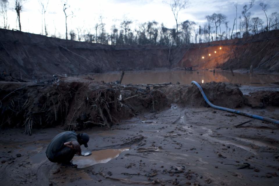 In this May 3, 2014 photo, an informal miner works to separate flecks of gold from the sandy, alluvial soil, using mercury to bind inside the crater of a gold mine process in La Pampa in Peru's Madre de Dios region. The clock has run out for the thousands of illegal gold miners who had until April 19 to legalize their status in a region of southeastern Peru where fortune-seekers have ravaged rainforests and contaminated rivers. (AP Photo/Rodrigo Abd)