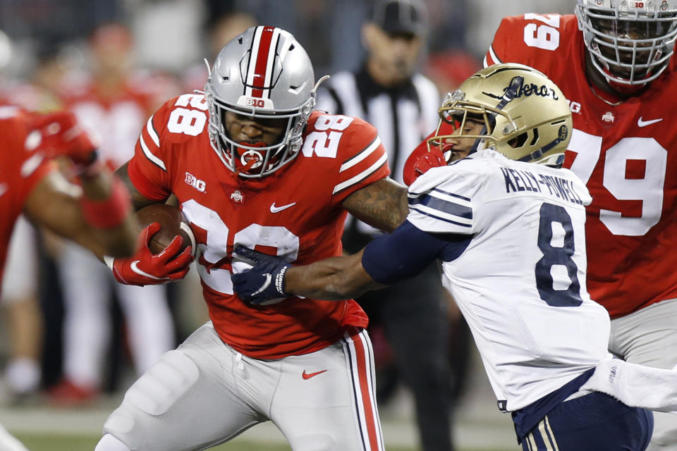 Ohio State running back Miyan Williams, left, fights his ways across the line of scrimmage against Akron defensive back Jaylen Kelly-Powell during the first half of an NCAA college football game Saturday, Sept. 25, 2021, in Columbus, Ohio. (AP Photo/Jay LaPrete)