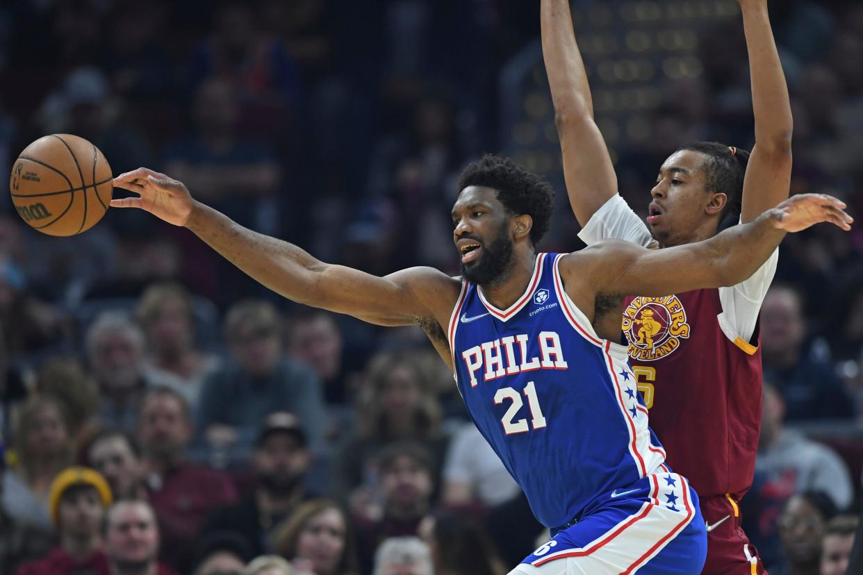 Philadelphia 76ers center Joel Embiid (21) turns the ball over while being pressured by Cleveland Cavaliers center Moses Brown (6) in the first half of an NBA basketball game, Sunday, April 3, 2022, in Cleveland. (AP Photo/David Dermer)